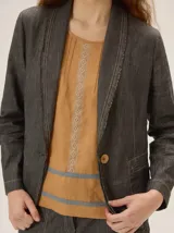 Blazer de lino color negro con pespuntes en contraste, solapas y cierre frontal con un botón.