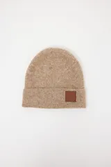 Gorro tejido de punto con doblez en el borde y aplique de cuero sintético con logo grabado en el frente.