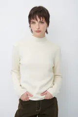 Polera de tejido de punto fino en color beige, con cuello alto y mangas largas con puños acanalados.