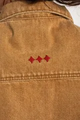 Chaleco de jean tostado con efecto lavado, cuello camisero, cierre frontal con botones metálicos y bolsillos delanteros con solapa. Diseño sin mangas y corte al cuerpo.