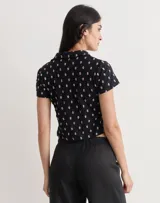 Camisa de manga corta color turquesa, confeccionada en tela de encaje con diseño floral. Presenta cuello camisero y cierre frontal con botones.