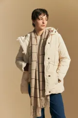 Campera acolchada de nylon en color crema, con capucha ajustable, cierre frontal con botones y cordón de ajuste en la cintura.
