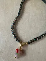 Collar con dije de corazón facetado en color verde esmeralda, con cadena de cuentas de cristal facetadas en tonos amarillos y dorados.