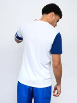 Remera de fútbol blanca con manga derecha azul marino y manga izquierda blanca con una banda azul marino y detalles rojos. Tiene el escudo del Club Nacional de Football en el pecho.
