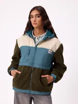 Campera con capucha, confeccionada en una combinación de materiales que incluye sherpa, pana y nylon. Presenta un diseño de bloques de color en tonos verde oliva, azul y beige, con cierre frontal, bolsillos laterales y parche de la marca en el pecho.