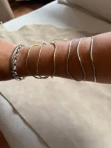 Pulsera rígida de metal con tres aros irregulares, disponible en alpaca color plateado o bronce color dorado.