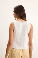 Musculosa de punto color blanco crudo, con escote en V y terminaciones con bordado artesanal amarillo.