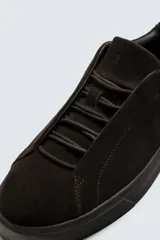 Zapatilla de estilo urbano confeccionada en piel con acabado de serraje. Presenta un diseño minimalista con cordonera oculta y suela de goma a contraste.