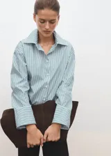 Camisa de popelín de algodón orgánico con diseño oversize, cuello camisero, manga larga con puños abotonados y cierre frontal de botones.