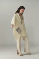 Chal de lana fina sin teñir con diseño de cuadros sutiles, cierre frontal con alamar y bolsillos de cuero metalizado. Presenta terminaciones con flecos en el ruedo y un calce estructurado en los hombros.