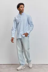 Camisa de manga larga en color celeste con estampado de rayas verticales finas, cuello abotonado y cierre frontal con botones.