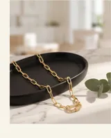 Collar de eslabones rectangulares de acero dorado, con un dije de cierre tipo mosquetón ovalado microdiamantado con circonias blancas.