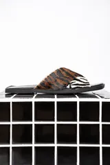 Sandalias chatas con base cuadrada negra y tiras cruzadas de cuero con estampado animal print de cebra y tigre.