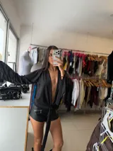 Top negro de satén con mangas largas acampanadas y diseño de nudo frontal, estilo escotado.