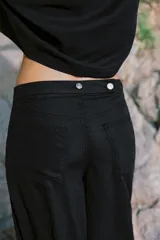 Jeans negro de tiro medio con corte balloon fit, diseño de cinco bolsillos y bajo acabado en puño con abertura y botón.