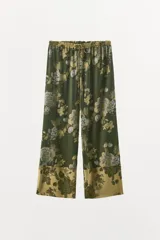 Pantalón de tiro medio confeccionado en mezcla de viscosa, con cintura elástica ajustable mediante cordón y diseño holgado. Presenta un estampado floral en tonos verde oscuro y beige, con detalle de panel contrastante en el bajo.