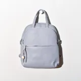 Mochila de cuero sintético color celeste con cierre superior y bolsillo frontal con cierre. Tiene asa de mano y correas ajustables para los hombros.