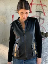 Campera negra de cuero con mangas largas de lana y bolsillos frontales con detalles dorados.