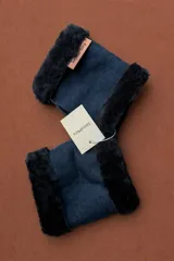 Guantes de cuero color azul marino con interior y bordes de piel sintética negra. Presentan una etiqueta de marca en cuero color suela.