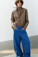 Jeans de tiro medio estilo balloon en color negro, con diseño de cinco bolsillos, trabillas para cinturón y cierre frontal con cremallera y botón metálico.