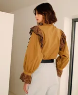 Camisa color marrón con cuello clásico, mangas largas abullonadas con puños elásticos y detalles de encaje floral en hombros y puños.