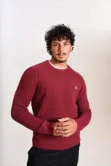 Sweater de punto grueso con cuello redondo y manga larga. Presenta un diseño de tejido acanalado y el logo de la marca bordado en el pecho.