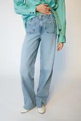 Jeans de tiro alto con corte wide leg y pernera ancha. Presenta bolsillos de plastrón en el delantero y cierre frontal con cremallera y botón.