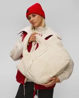 Bolso tote de sherpa color crema, con asas de mano y correa bandolera ajustable. Cuenta con cierre de cremallera y bolsillos internos.