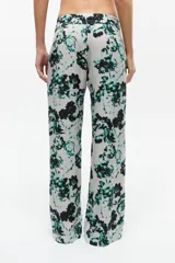 Pantalón de tela fluida con estampado floral en tonos gris, verde y negro, con cintura elástica y corte recto.