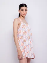 Vestido corto blanco con estampado floral en tonos naranja y lila, de corte suelto y sin mangas.