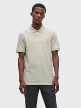 Polo de hombre color beige claro, confeccionado en tejido piqué de algodón. Presenta cuello y tapeta de tres botones, mangas cortas con borde a contraste y logo bordado sutil en el pecho.