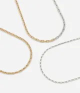 Collar de tres capas confeccionado en metal con baño mixto, que combina cadenas de diferentes estilos y eslabones en tonos dorados y plateados.