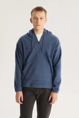 Buzo azul de polar con capucha, cierre parcial con cremallera, bolsillo tipo canguro y logo bordado en el pecho.