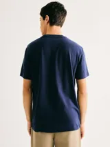 Camiseta blanca de algodón con cuello redondo y mangas cortas. Estampa rectangular con borde negro que contiene la frase "NATURAL ATMOSPHERE" en letras mayúsculas y una imagen de montañas y mar.