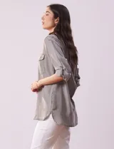 Camisa celeste de tencel con cuello con solapa, abertura central con botones ocultos, bolsillos delanteros y mangas largas regulables con presilla y botón.