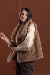 Chaleco de piel sintética en color marrón, con diseño de corte recto y largo a la cadera. Presenta un cuello amplio con caída envolvente y cierre frontal oculto, con interior forrado.