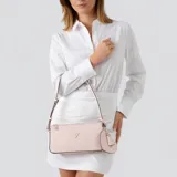 Cartera tipo baguette Guess modelo Isobel, color rosa, con diseño estructurado, cierre superior, herrajes dorados y logo triangular frontal. Incluye un charm colgante en forma de corazón y correa ajustable.