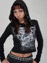 Remera de manga larga con capucha integrada, color negro con estampado gráfico frontal en blanco. La capucha presenta detalles de ojales metálicos decorativos.