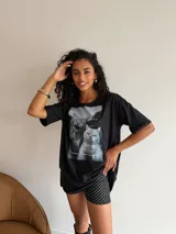 Remeron negro de corte oversize con estampa fotográfica frontal de dos gatos y texto alusivo. Presenta cuello redondo y mangas cortas.