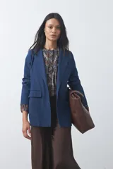 Blazer de jean color celeste con silueta recta y corte sastrero. Presenta solapas clásicas, cierre frontal con botón forrado, bolsillos con tapa y detalle de botones forrados en los puños.