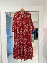 Vestido largo rojo con estampado botánico en tonos beige, escote en V con botones frontales, mangas tres cuartos con volados y diseño escalonado en la falda.