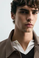 Sobrecamisa negra de corte boxy fit en tejido compacto, con cuello solapa, manga larga con puño abotonado, bolsillos frontales aplicados y cierre frontal de botonadura.