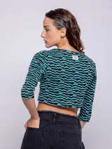 Top corto negro con estampado de líneas onduladas blancas, mangas 3/4 y abertura circular en el pecho.