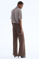 Pantalón de corte bootcut con estampado de pata de gallo en tonos marrones. Presenta cierre frontal con pretina prolongada, botón oculto y corchetes, además de raya marcada en la parte delantera y trasera, bolsillos laterales al bies y bolsillos traseros ribeteados.