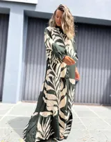 Vestido largo camisero de manga larga, con cuello mao y botones frontales. Presenta un estampado grande de hojas en color verde oscuro y crudo, con corte en capas en la falda.