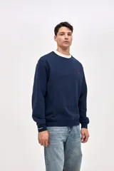 Buzo de cuello redondo en felpa con friza, color azul marino con detalle de cuello en color crema. Presenta bordado de la marca en el pecho y en el puño de la manga.