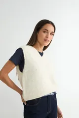 Chaleco de punto color crema con escote en V, sin mangas y diseño decorado con pequeñas perlas aplicadas en toda la superficie.