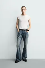 Jeans flare fit de tiro medio, confeccionados en denim de algodón color azul con efecto deslavado. Diseño ajustado en la parte superior y abierto en campana desde la rodilla, con cinco bolsillos y cierre frontal con cremallera y botón.