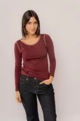 Remera de manga larga color bordó, confeccionada en algodón suave. Presenta un diseño de cuello redondo con costuras a la vista en contraste de color, que se extienden también por las sisas.