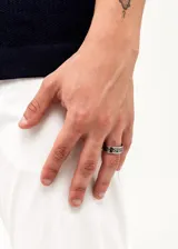Anillo plateado de acero quirúrgico con diseño de grecas negras.